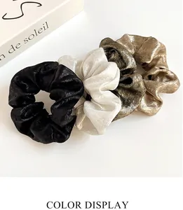 Quatre chouchous métalliques en noir, blanc, or et champagne avec une texture scintillante