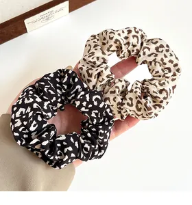 Detail view of two leopard print scrunchies in cream and black elastic fabric