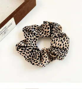 Macro detail of leopard print satin scrunchie showing glossy fabric and texture