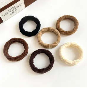Close-up of six ribbed elastic hair ties in earth tones on a clean white background