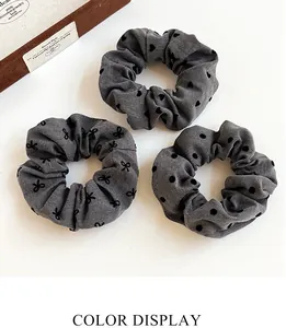 Three-piece set of grey polka dot and heart print elastic scrunchies on white background