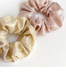Détail de deux chouchous scintillants en or champagne et rose métallisé soyeux