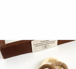 Detailed view of cream and coffee high elasticity ribbed hair ties on felt tray
