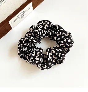 Detailed view of leopard print scrunchie fabric texture and elastic design