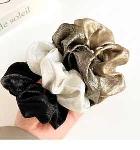 Détail de chouchous métalliques élégants en or, argent et noir avec une texture soyeuse