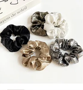 Cinq chouchous en soie métallisée or argent et noir avec une texture plissée élégante