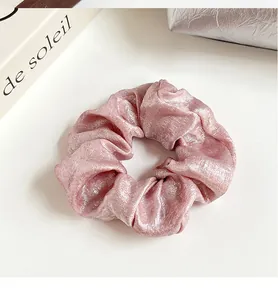Gros plan du chouchou en soie rose métallisée montrant la texture et l'éclat