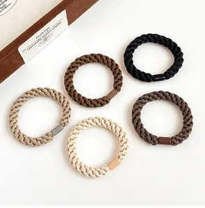 Close-up of five thick elastic hair ties in neutral tones on a white background