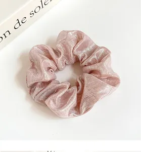 Détail d'un chouchou rose perlé avec une texture rayée métallique élégante