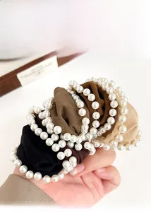 Detailed view of elastic wide pearl hair scrunchies in various elegant neutral colors
