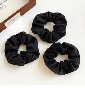 Three-piece black scrunchie set with polka dots, bows, and heart flocked patterns