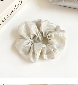 Gros plan d'un chouchou en soie métallique avec plis riches et texture élastique