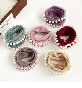 Detailed view of six velvet hair scrunchies with white faux pearl edges in varied colors