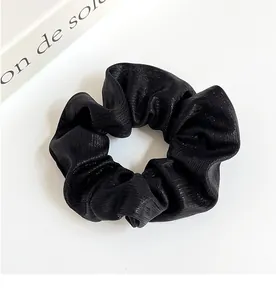 Vue détaillée du chouchou noir scintillant avec tissu élastique et détails plissés