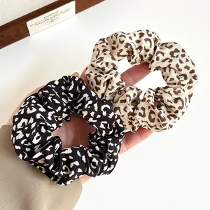 Set of two vintage leopard print silk scrunchies held by hand for elastic hair ties