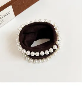 Detail view of double-layered faux pearls on a deep brown elastic hair scrunchie