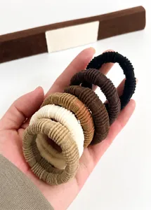 Set of thick ribbed hair ties in earthy tones held to show elastic texture and colors