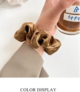 Dettaglio dell'elastico in raso color bronzo con texture setosa sui capelli della modella