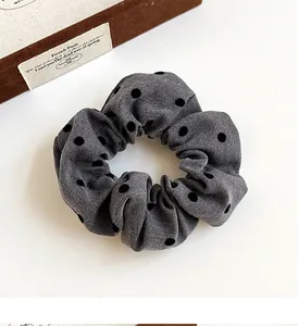 Close-up of a grey polka dot hair scrunchie with soft twill texture and high elasticity