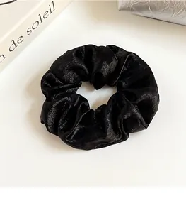 Détail d'un chouchou noir plissé haute élasticité avec une texture de soie brillante