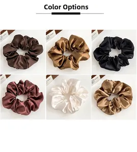 Dettaglio di elastici scrunchies in raso in sei toni terra con texture lucida e setosa