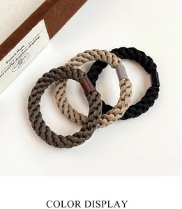Detailed view of three thick braided elastic hair ties in brown and black earthy tones