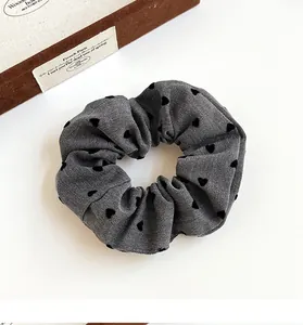 Close-up of gray scrunchie with black heart pattern on twill cotton fabric texture