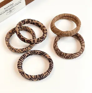 Detail of five leopard and animal print hair ties in earthy tones on a white surface