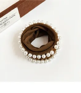 Detail of a brown elastic scrunchie featuring elegant double-row white pearl decorations