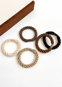 Detail of five earth-toned woven hair ties with elastic texture and secure plastic joints