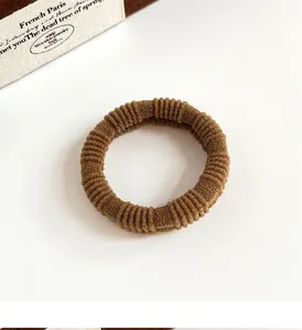 Detailed macro view of the durable ribbed texture and elastic band of this brown hair tie
