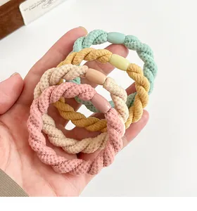 Détail de quatre élastiques à cheveux tressés en rose, crème, jaune et vert pastel