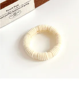 Detailed view of the creamy beige elastic scrunchie featuring a soft ribbed knit texture