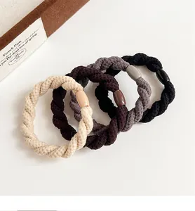 Gros plan de quatre élastiques à cheveux tressés en beige, marron, gris et noir élégant