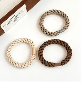 Close-up of thick braided elastic hair ties in khaki and brown tones with matte clasps