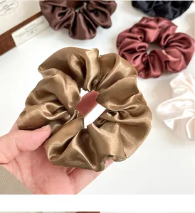 Dettaglio degli elastici scrunchie in raso lucido color bronzo e bordeaux seta