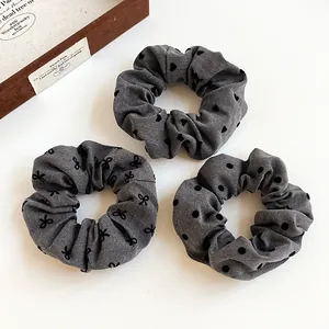 Three-piece set of grey patterned scrunchies with heart, bow, and polka dot designs