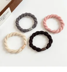 Détail de quatre élastiques à cheveux tressés épais en gris, rose, beige et marron foncé