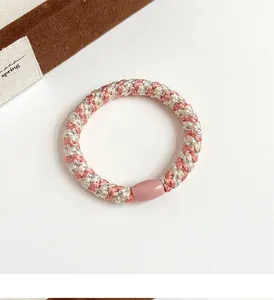 Vue détaillée d'un chouchou tressé rose et beige avec fermoir ovale sur fond blanc