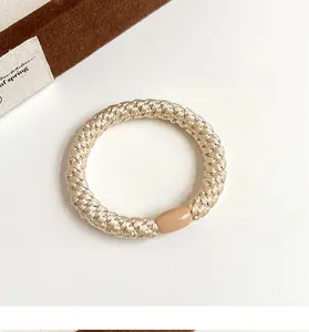 Détail d'un élastique à cheveux tissé main champagne avec boucle lisse et texture épaisse