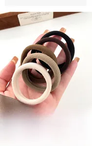 Détail d'élastiques à cheveux sans couture haute élasticité tenus à la main ton café