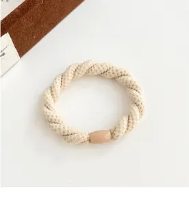 Détail d'un élastique à cheveux tressé beige avec design torsadé et fermoir lisse