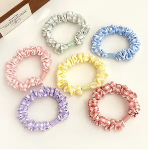 Detailed view of six plaid fabric hair scrunchies in pastel colors with matching plastic buckles