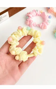 Gros plan d'un chouchou à froufrous jaune avec perles pastel pour coiffures douces