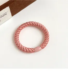 Détail macro d'un élastique rose tressé avec perle décorative lisse assortie