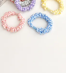 Close-up of pastel plaid fabric scrunchies in pink blue and yellow showing soft pleated texture