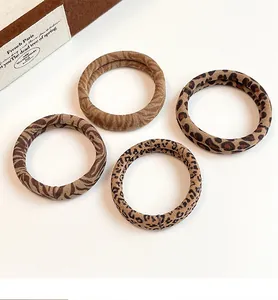 Detailed view of four leopard print scrunchies in earth tones on a white background