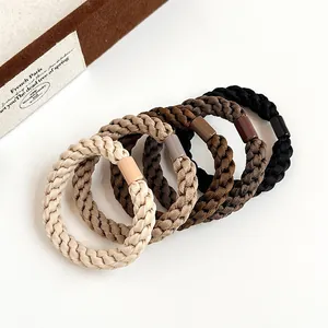Five pieces of thick elastic woven hair ties in various earthy coffee and beige tones