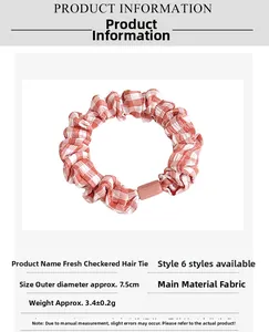 Detail of orange and white plaid hair scrunchie with 7.5cm outer diameter and pink buckle
