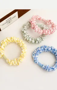 Detail showing four pastel plaid hair scrunchies in yellow blue pink and green tones
